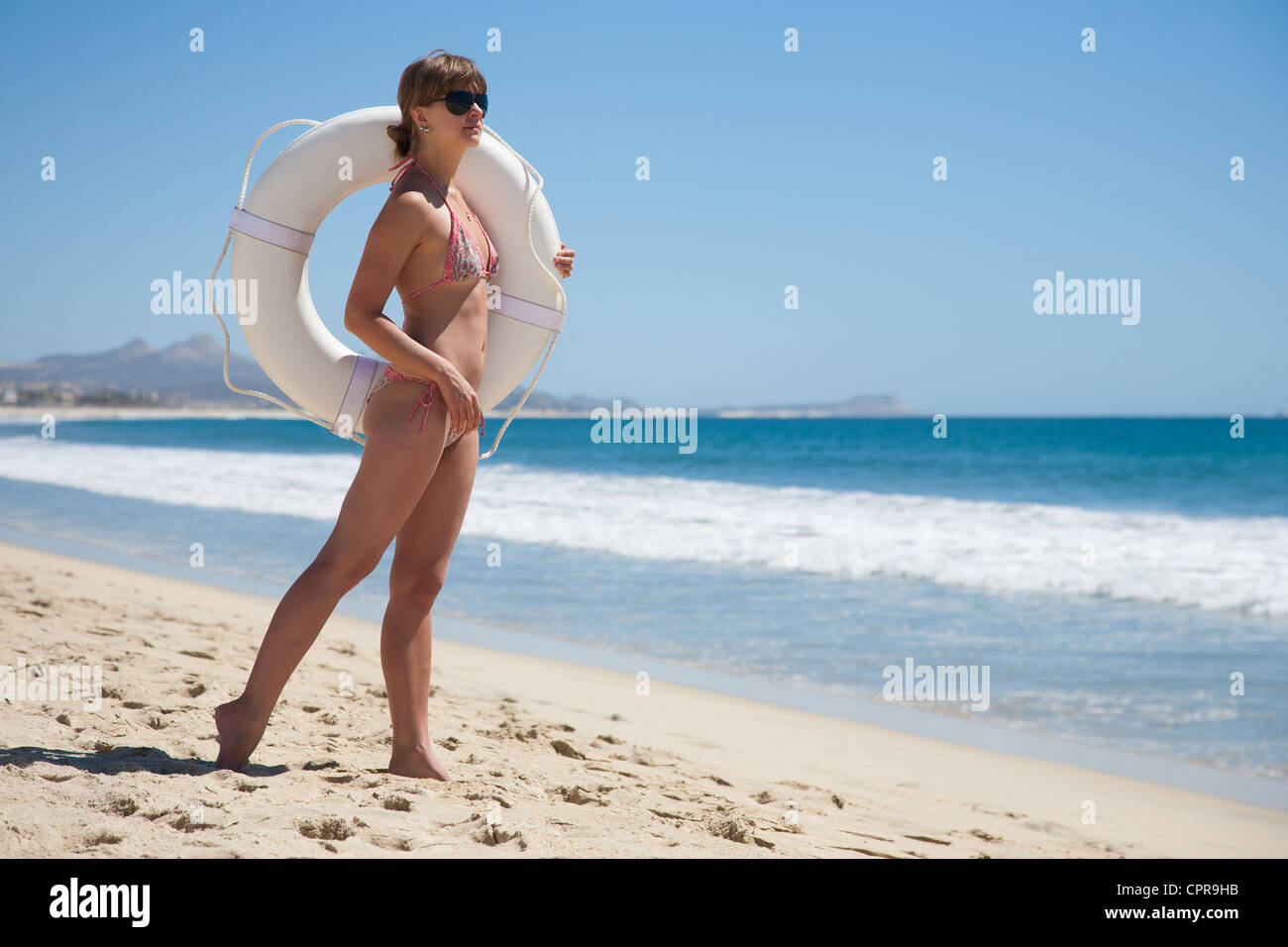 Junge Frau, die gerade der Bucht mit einem weißen Rettungsring Stockfoto