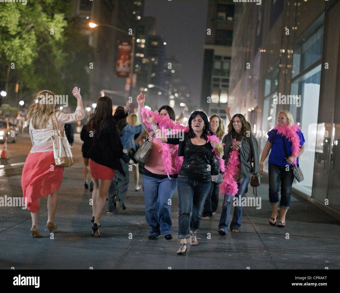 Frauen mit rosa Leis feiern in der Nacht in New York City. Stockfoto