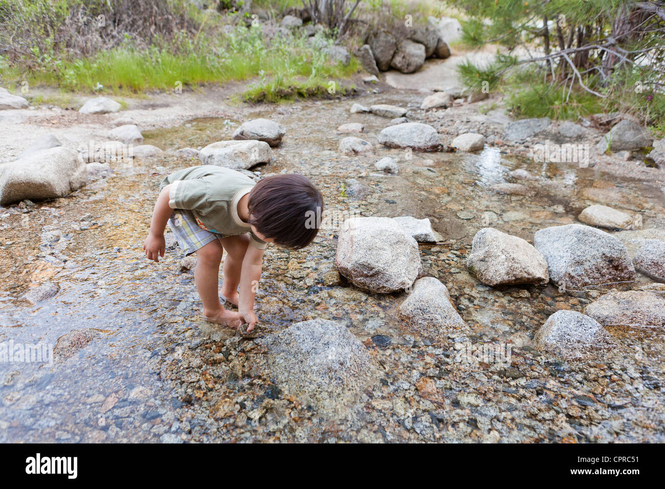 Kleine asiatische junge spielt in einem stream Stockfoto