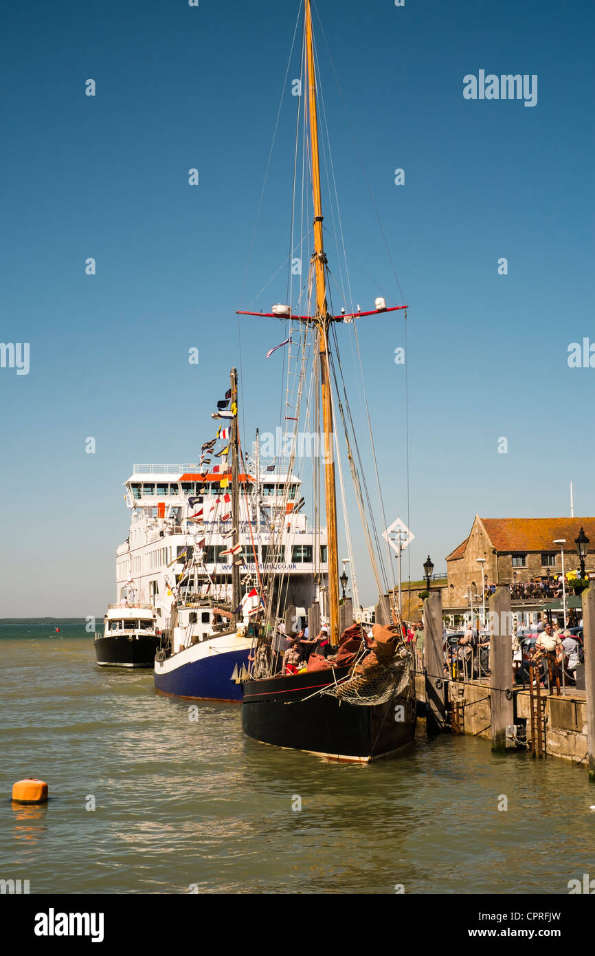 Schiffe und Nachtschwärmer mischen am Kai während des alten Gaffers Festivals in Yarmouth auf der Isle Of Wight. Stockfoto