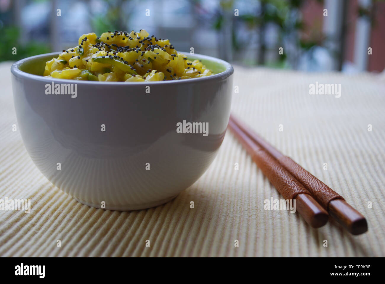 Gelber Reis mit Safran, Zwiebeln, Zucchini und Mohn Samen in einer Schüssel mit Stäbchen Stockfoto