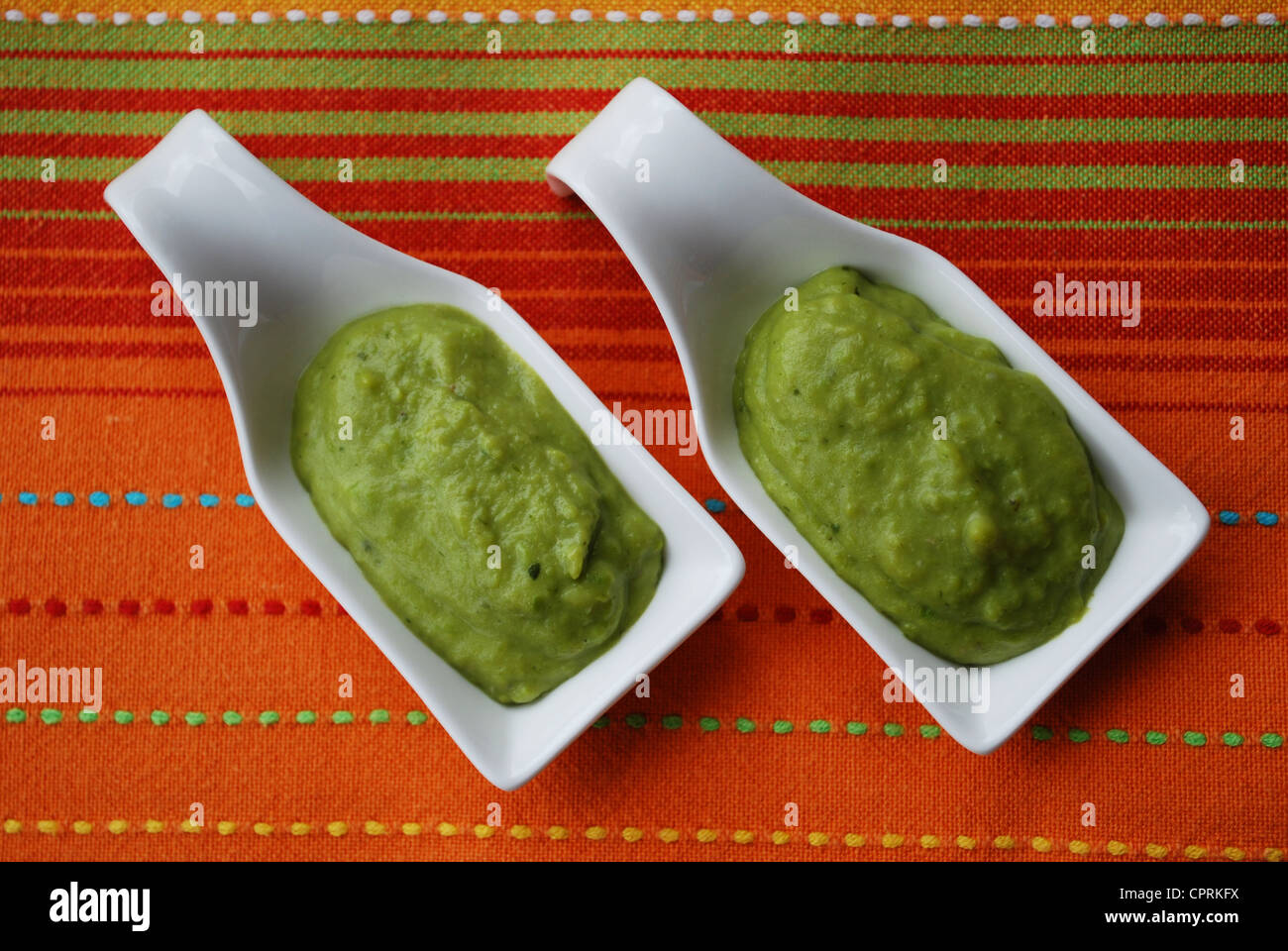 Grüne Bohnen Sahne mit Basilikum in Weißware Schale auf orange Stoff Hintergrund Stockfoto