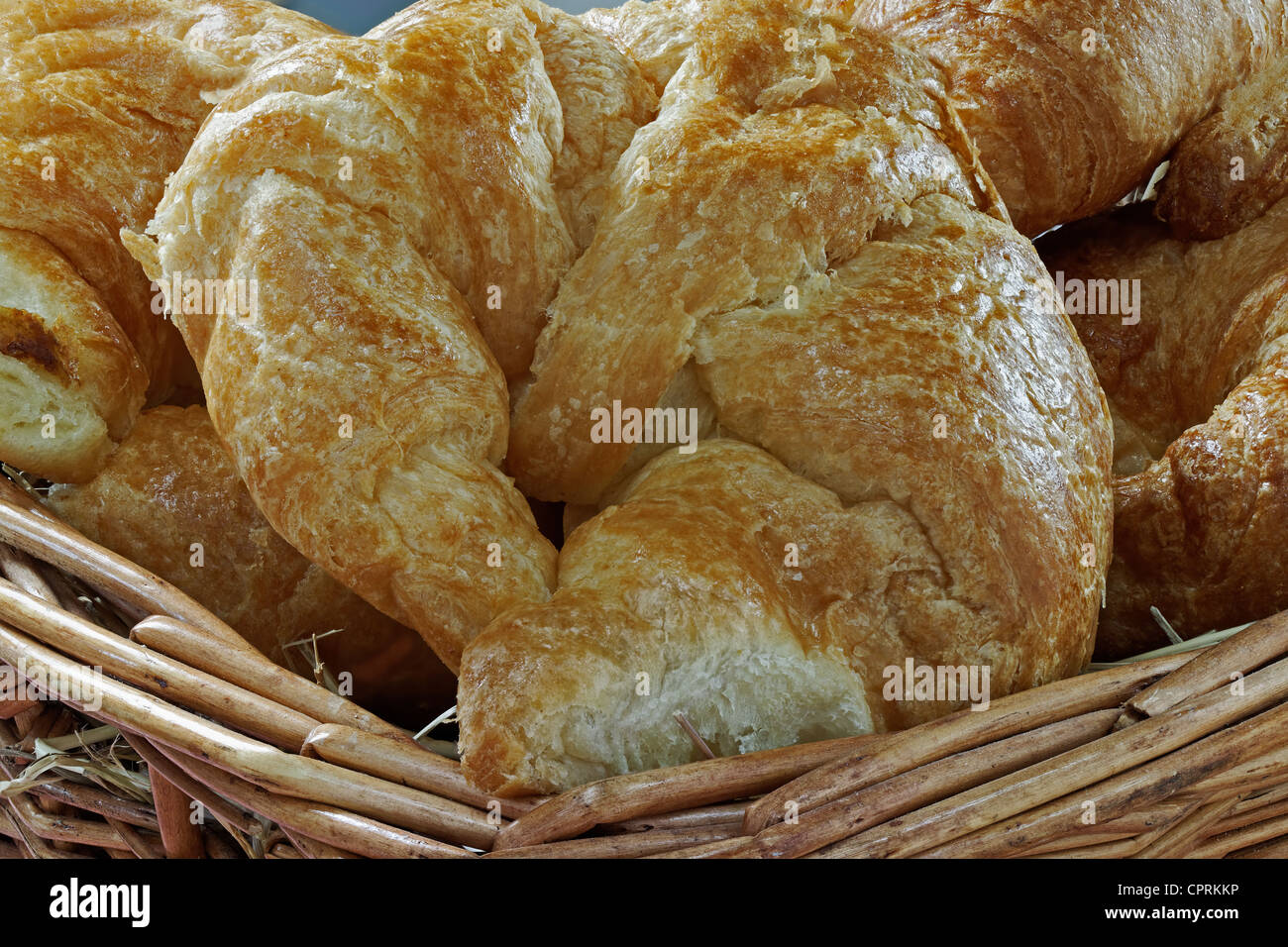 Eine Gruppe von frischen Croissants in einem Heu gefüllten Korb Stockfoto