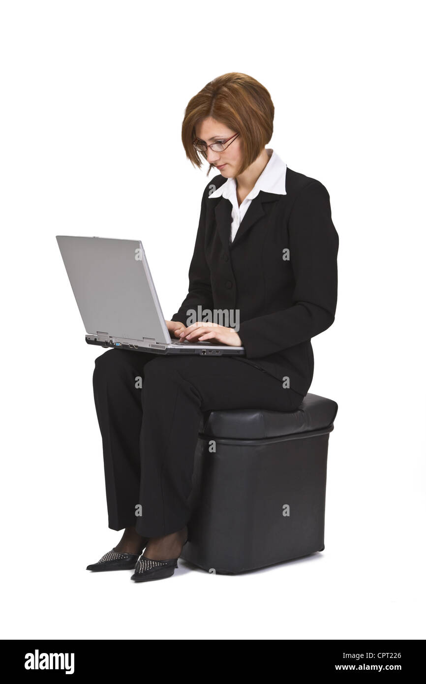 Geschäftsfrau auf Pouf sitzen und arbeiten auf einem Laptop. Stockfoto