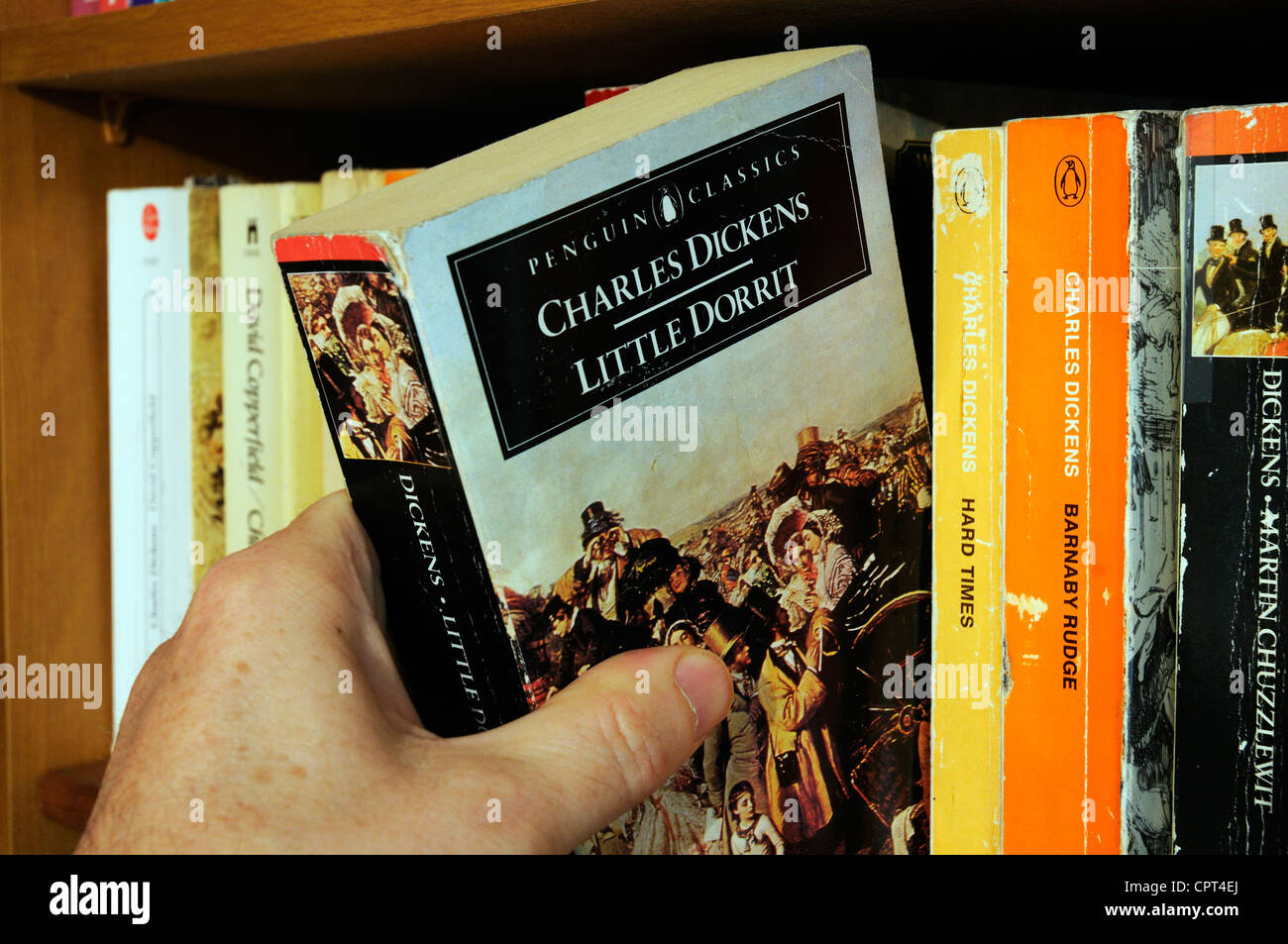 Eine Hand unter Charles Dickens Little Dorrit von einem Bücherregal Stockfoto