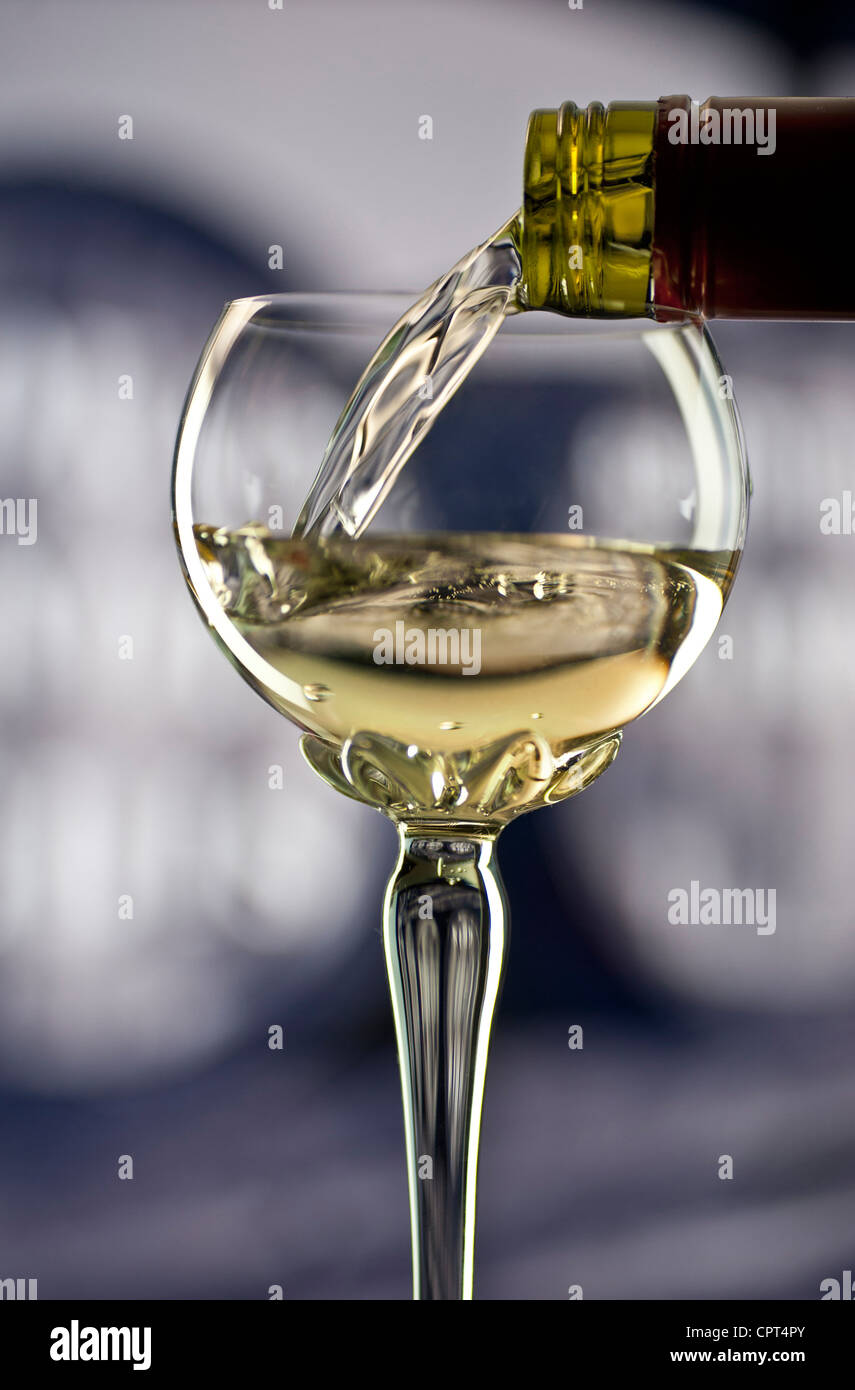 Weingießen, Glas weißen elsässischen Weines in traditionelles, langstieliges Deko-Riesling-Glas mit Weinfässern dahinter Stockfoto