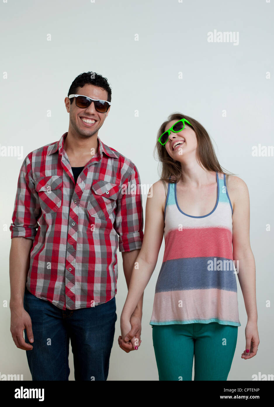 Junges Paar, das Tragen von Sonnenbrillen und lachen, Studioaufnahme Stockfoto