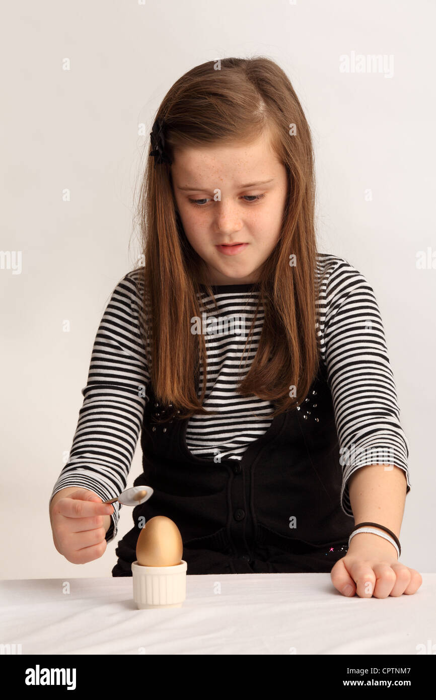 Konzeptbild eines neunjährigen Mädchens, das ein goldenes Ei aufbrechen wird. Stockfoto