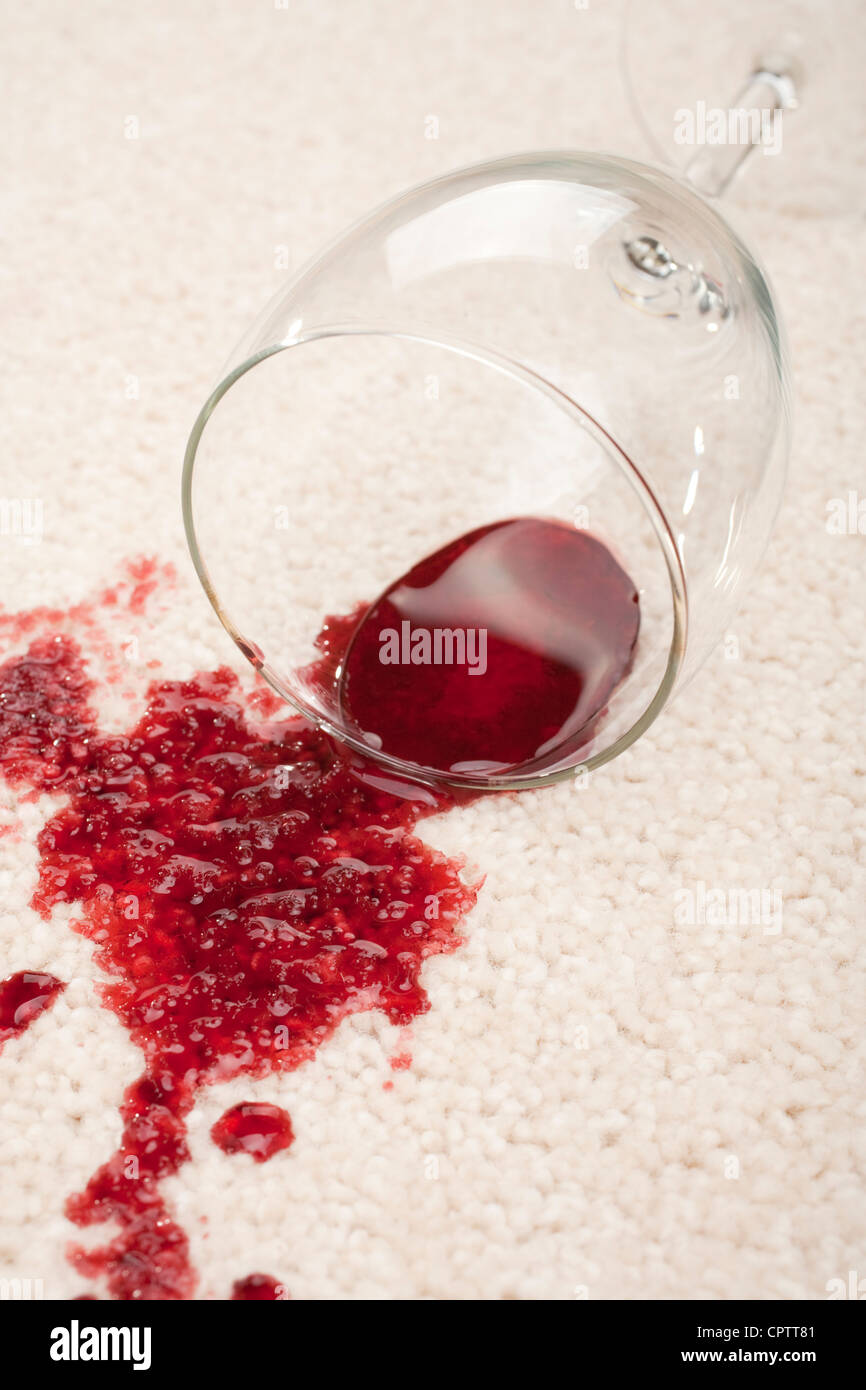 Ein verschüttetes Glas Rotwein auf einem Creme farbigen Teppich Stockfoto