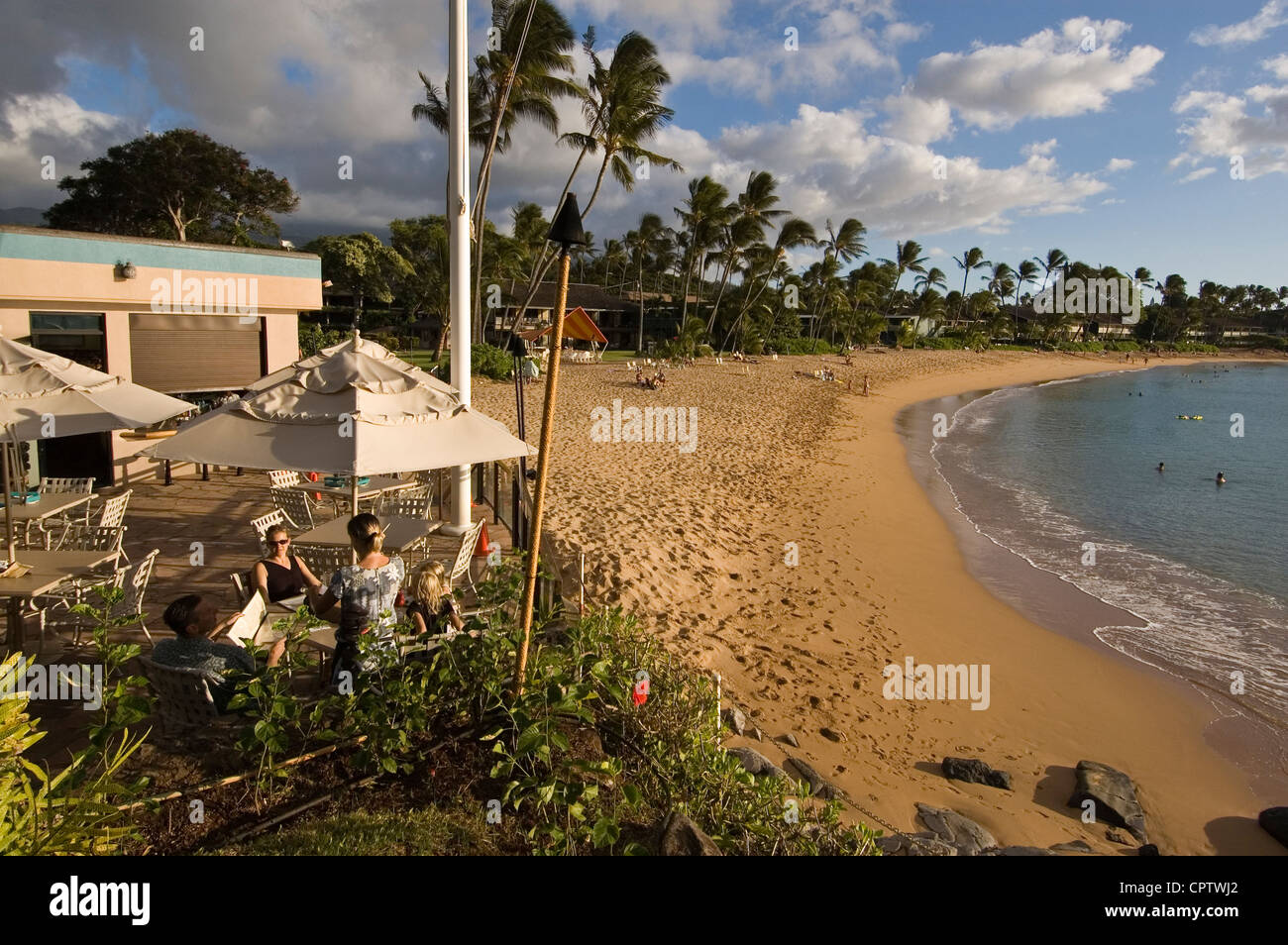 Elk284-4301 Hawaii, Maui, Kaanapali Coast Napili Bay Beach, Frauen in einem Outdoor-Restaurant, gesäumt von Palmen und hotels Stockfoto