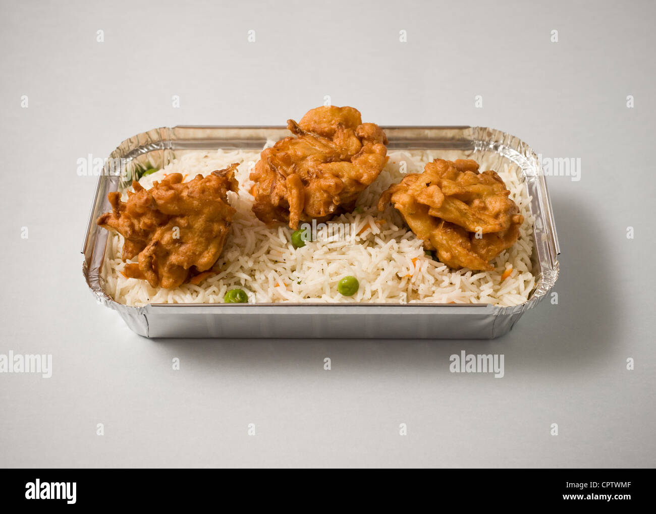 Reis mit Pakoras in eine Folie Box zum mitnehmen. Stockfoto