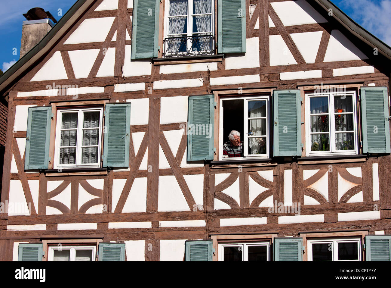 Mann am Fenster des traditionellen malerischen Fachwerk-Hauses in Schiltach in den Bayerischen Alpen, Deutschland Stockfoto