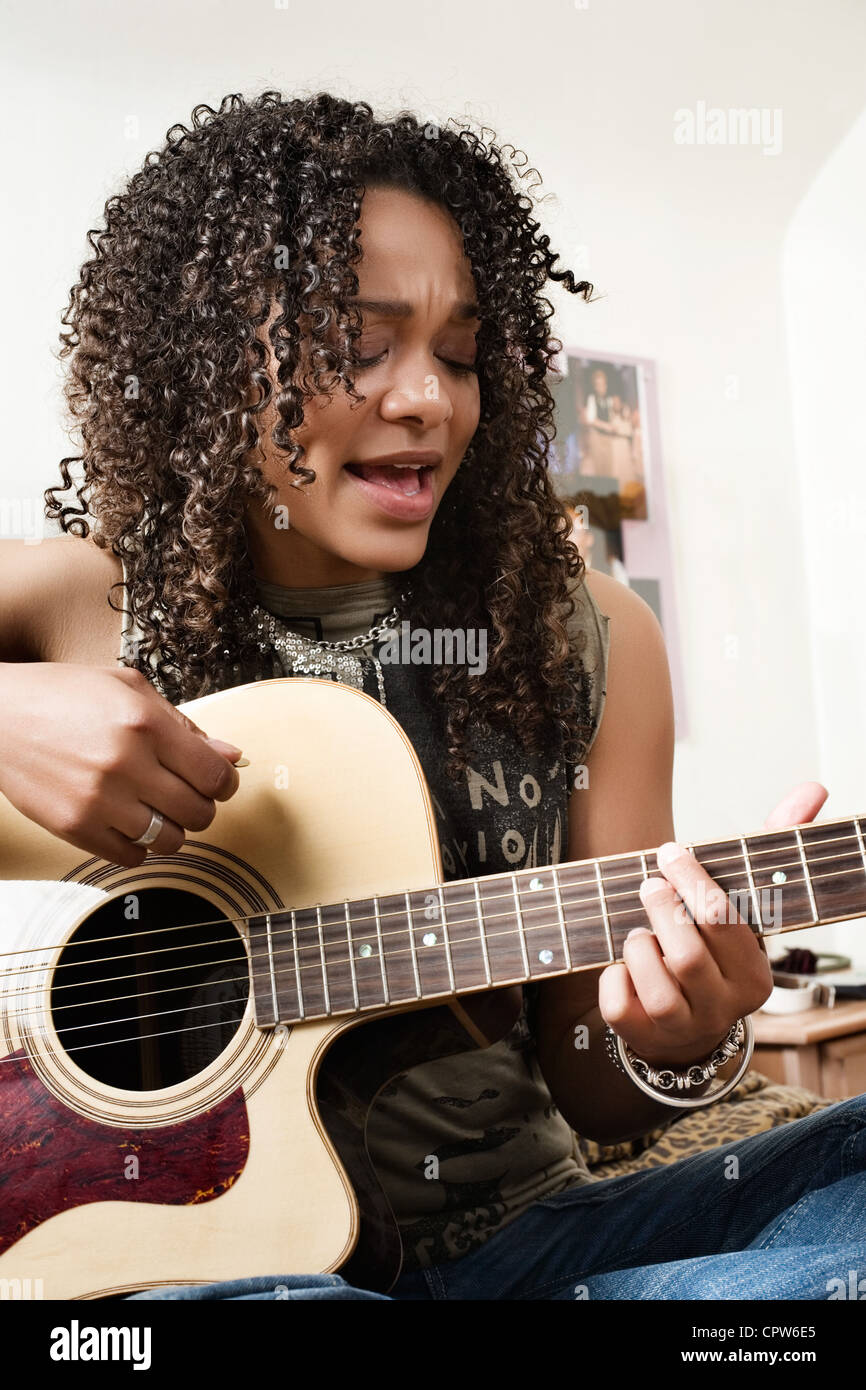 Junge Frau singt und spielt Gitarre Stockfoto