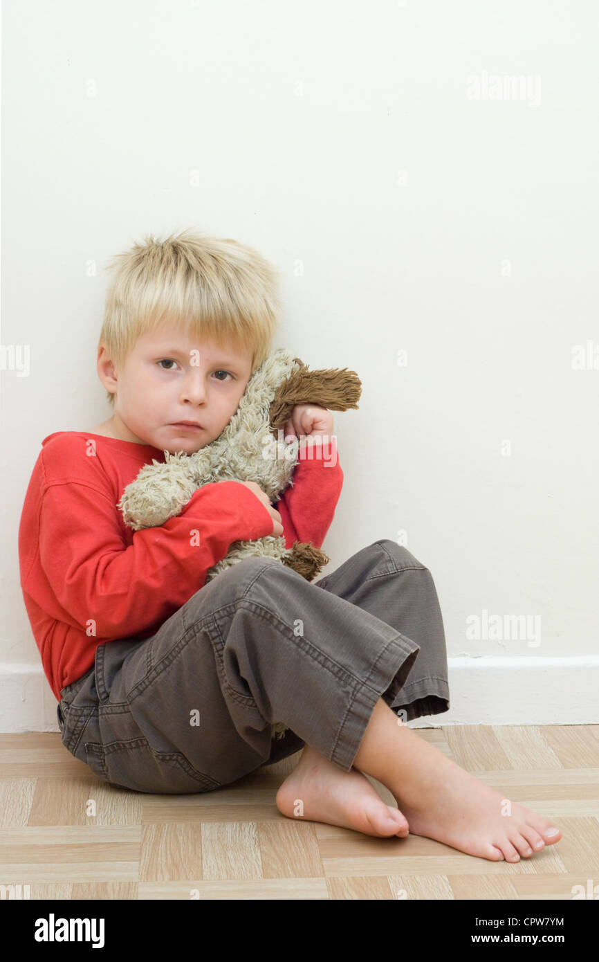 Einsames Kind sitzen auf dem Boden mit einem Stofftier. Stockfoto