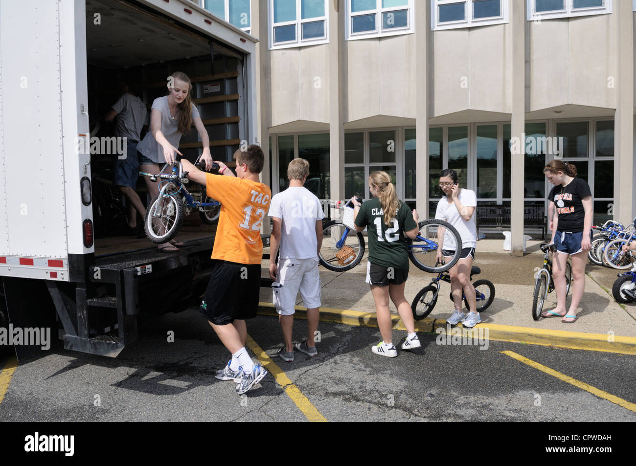 High School Student freiwilligen Zivildienst laden tun gespendet gebrauchte Fahrräder auf LKW, für die armen Länder zu verteilen. Stockfoto
