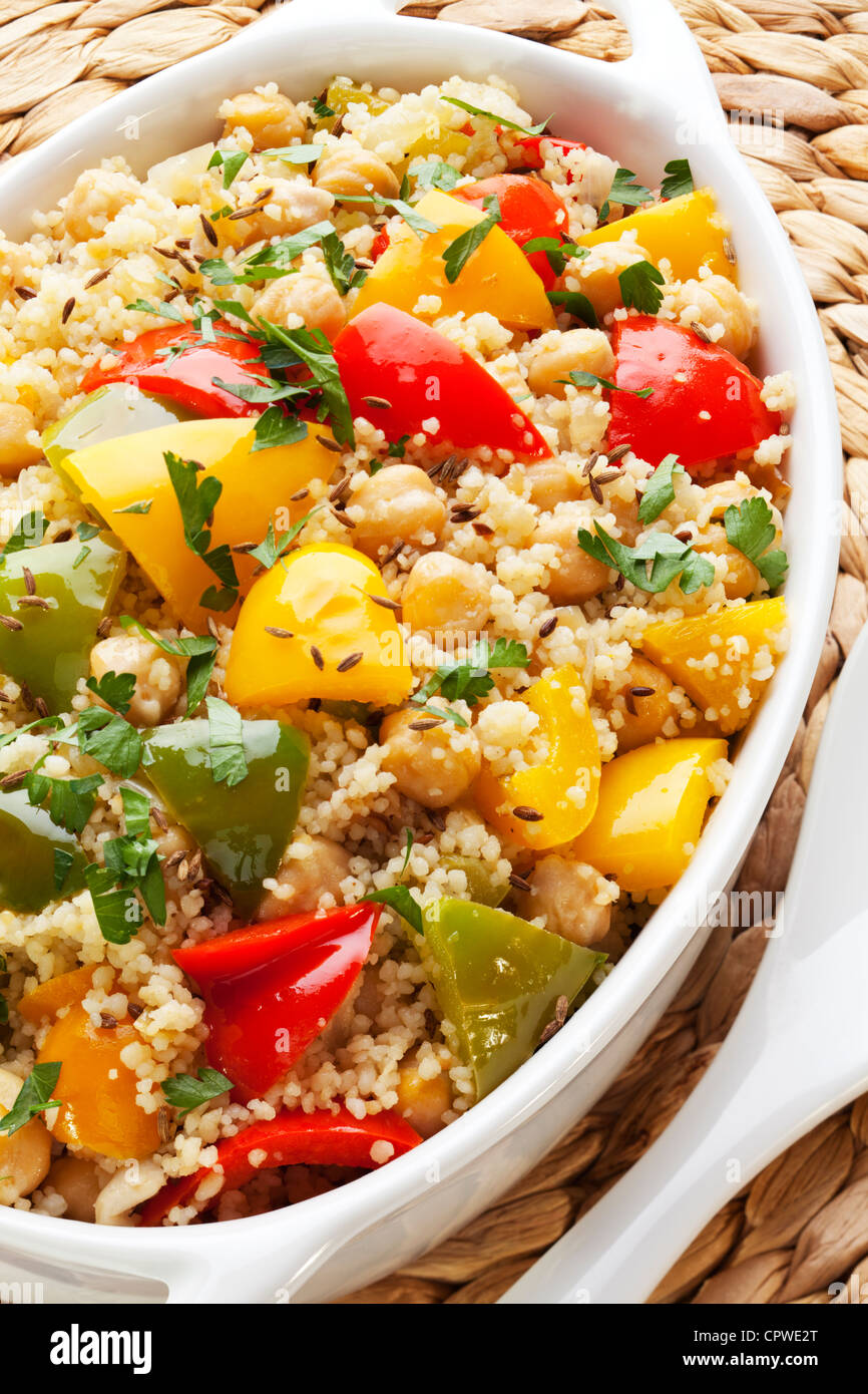 Couscous mit Kichererbsen, rote, grüne und gelbe Paprika, Zwiebeln, Kümmel und Petersilie, zubereitet mit Olivenöl extra vergine. Stockfoto