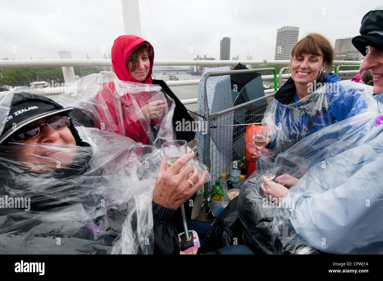 Flotte auf der Themse-vier Frauen tragen Kunststoff Ponchos trinken Champagner im Regen Stockfoto