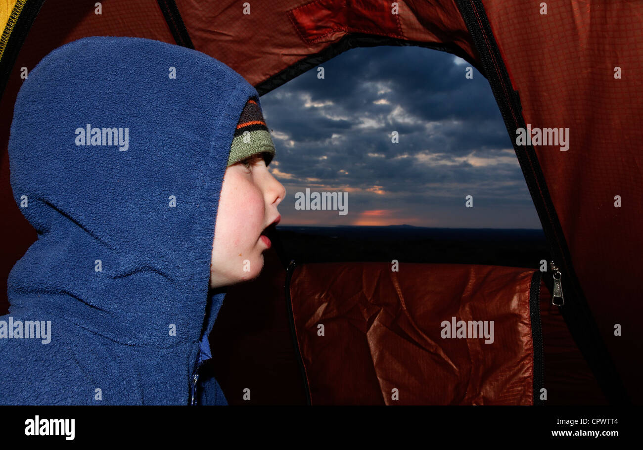 Ein kleiner Junge den Sonnenuntergang von einem Zelt Stockfoto