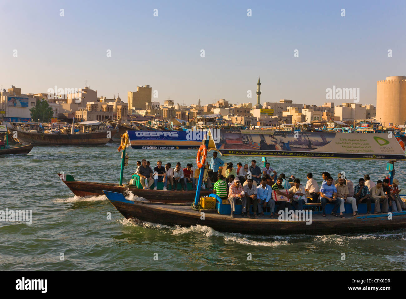 Fähre, Boote und Skyline entlang Khor Dubai (Dubai Creek), Dubai, Vereinigte Arabische Emirate Stockfoto