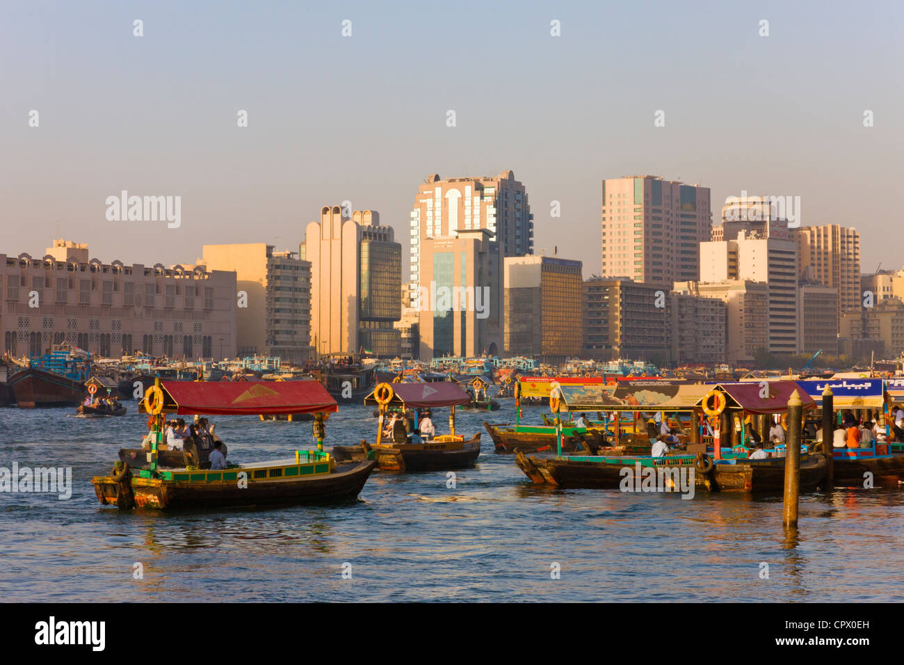 Fähre, Boote und Skyline entlang Khor Dubai (Dubai Creek), Dubai, Vereinigte Arabische Emirate Stockfoto