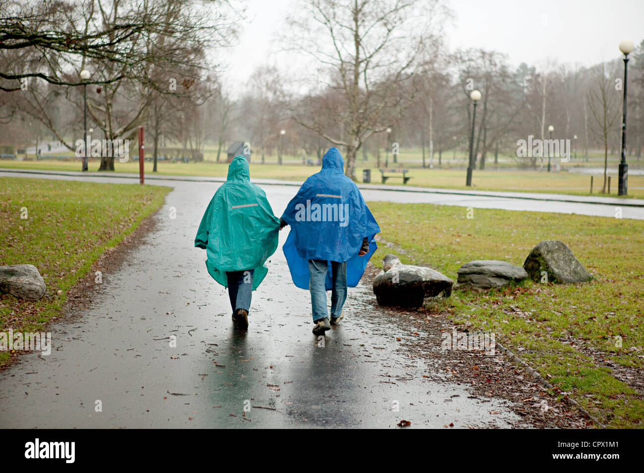 Älteres Paar in wasserdichte Kleidung zu Fuß durch den park Stockfoto