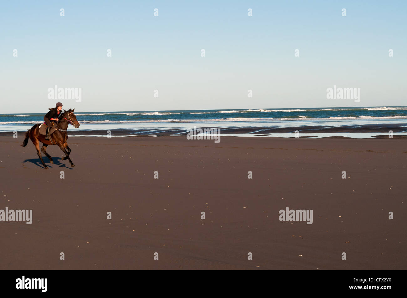 Mitte Erwachsene Frau Reiten am Strand Stockfoto