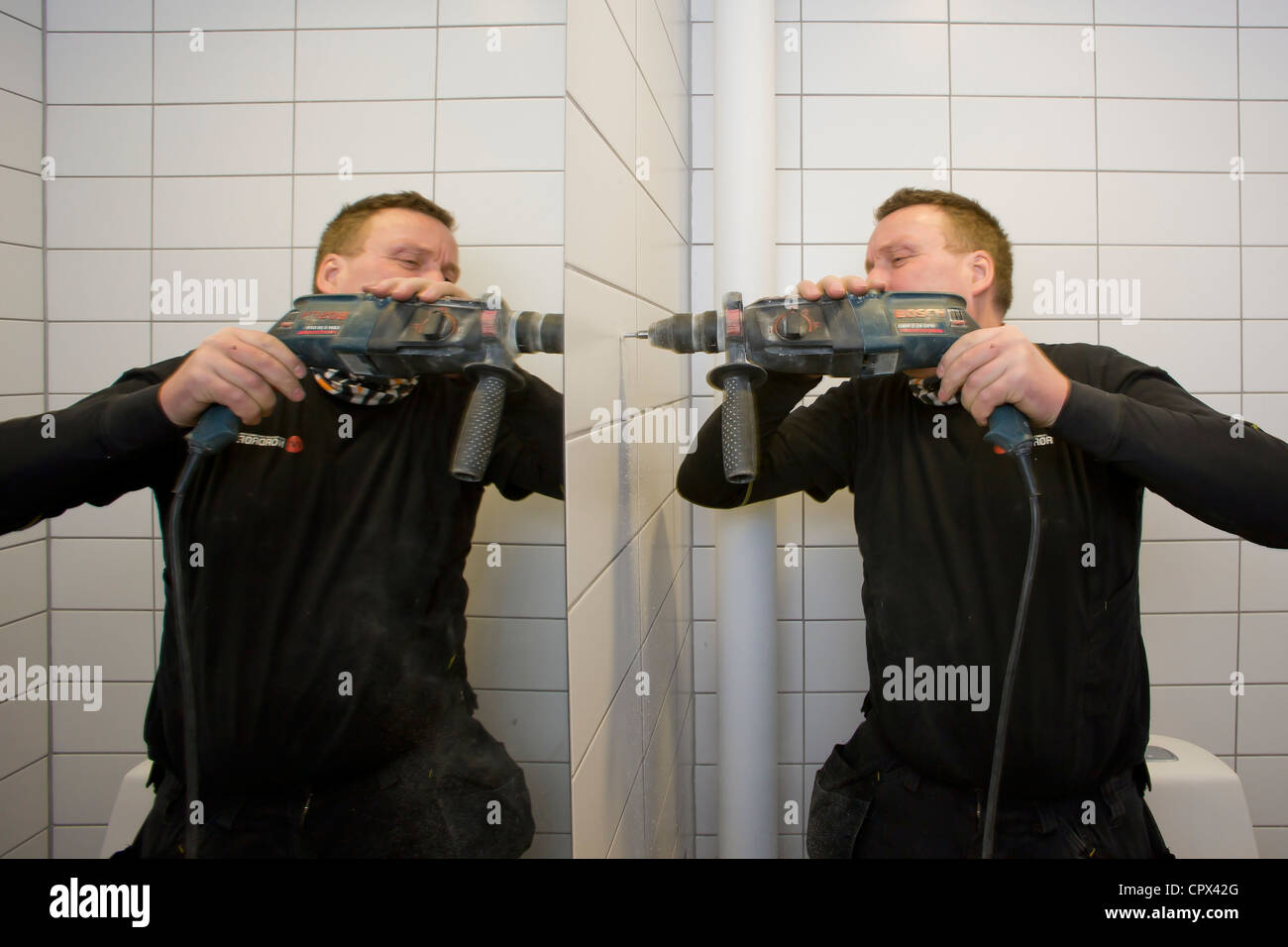 Heizungs- und Sanitär-Techniker Bohren von Löchern für Badezimmerausstattung Stockfoto