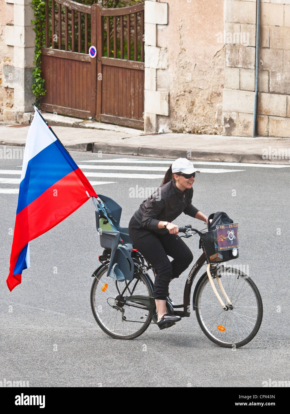 Weibliche Radfahrer mit Staatsflagge der Russischen Föderation auf ihrem Fahrrad - Frankreich. Stockfoto