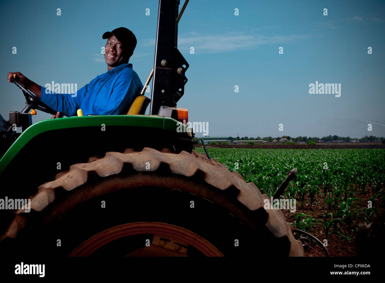 Schwarze Landarbeiter einen Traktor zu fahren lächelnd Stockfoto