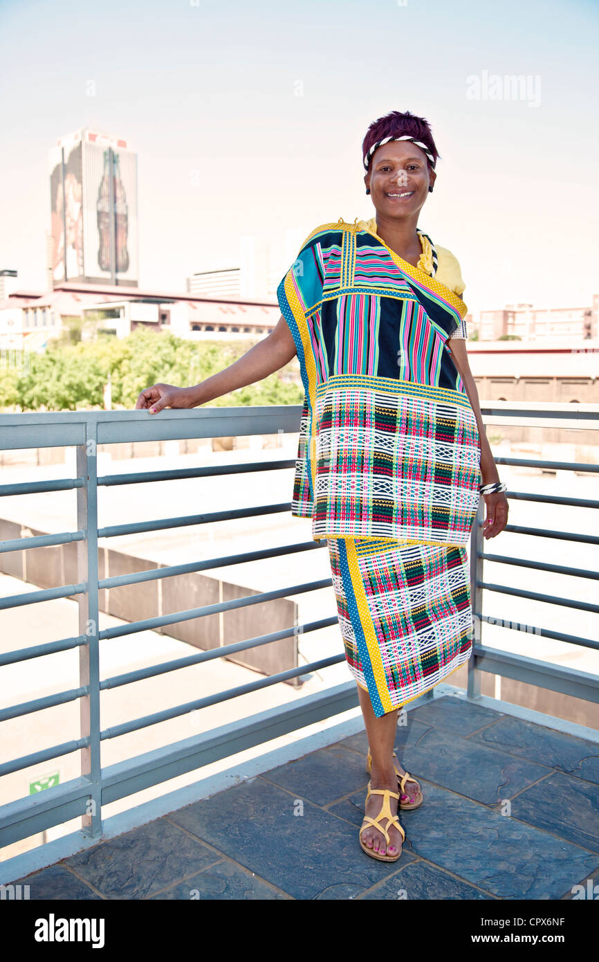 Afrikanische Frau, gekleidet in traditioneller Kleidung, stützte sich auf einen Balkon Stockfoto