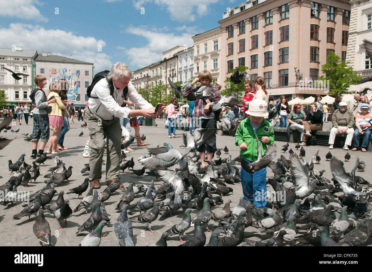 Mann nimmt Foto mit Handy zwischen Tauben in überfüllten Hauptmarkt, Krakau, Polen. Stockfoto