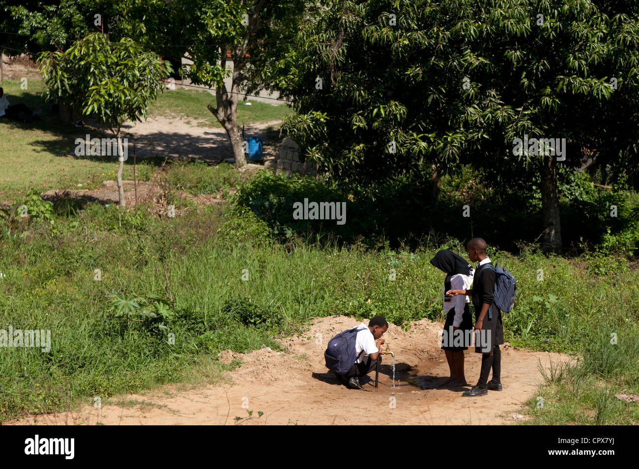 Drei Kinder trinken Wasser aus einem Hahn, im freien Stockfoto
