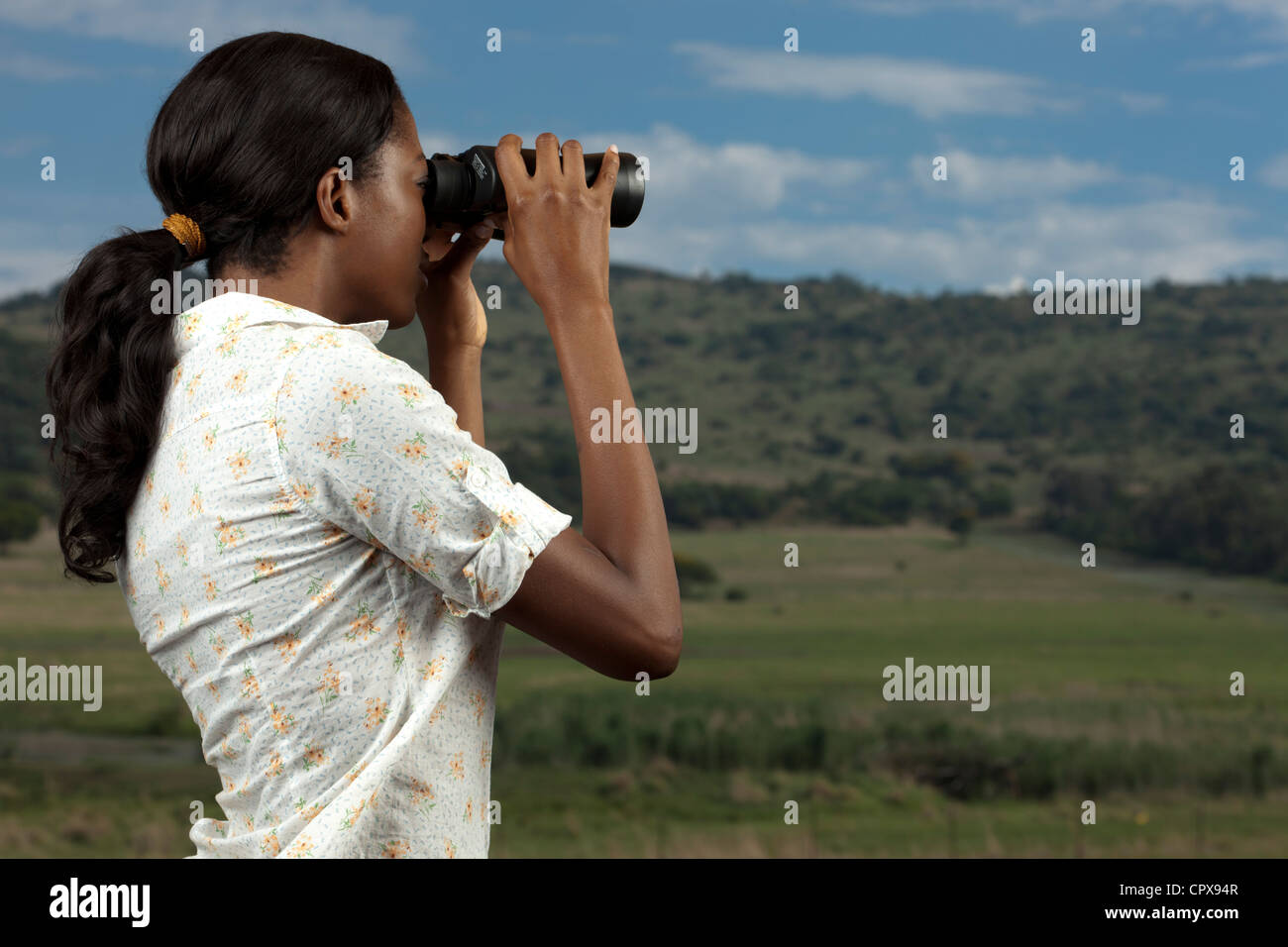 Eine afrikanische Frau sucht Tiere in einem Game Reserve durch ein Fernglas Stockfoto