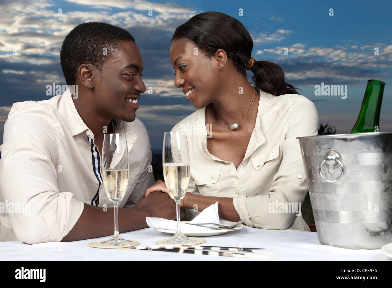 Eine afrikanische paar plaudern und trinken Champagner im Freien während des Sonnenuntergangs Stockfoto