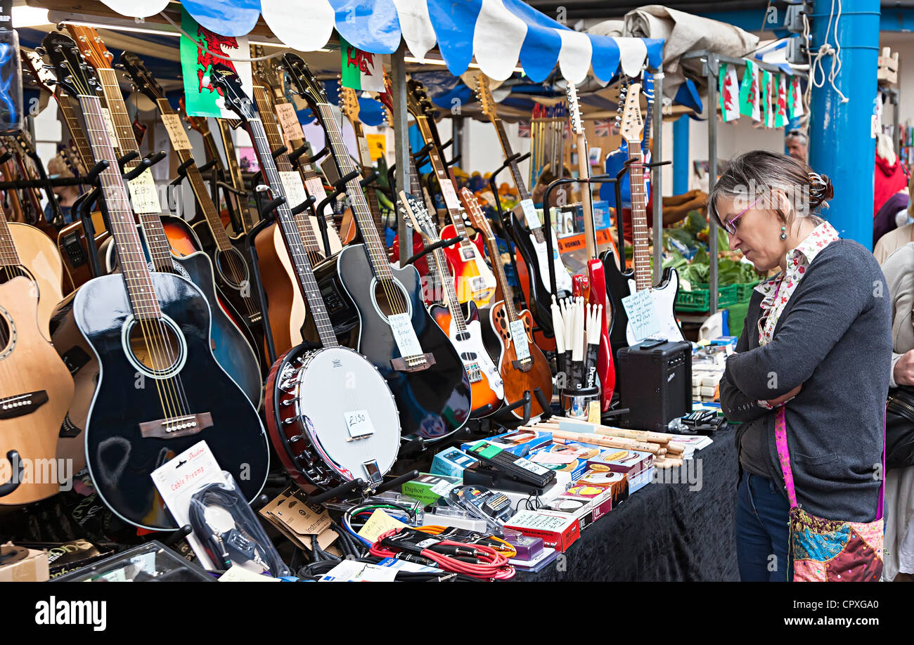 Frau betrachten Gitarren und Musikinstrumente zum Verkauf auf Marktstand, Abergavenny, Wales, UK Stockfoto