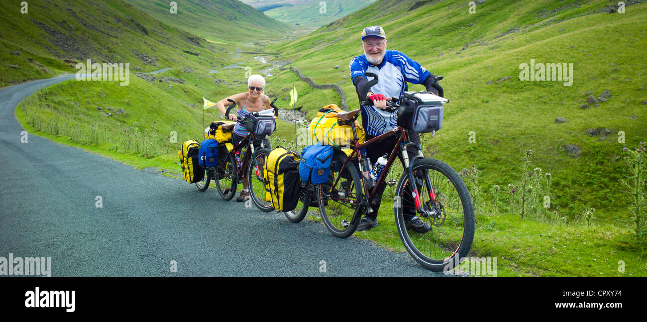 Radfahrer auf der Fahrbahn über den Wrynose Pass im Dudden Tal Teil des Lake District National Park, Cumbria, England Stockfoto