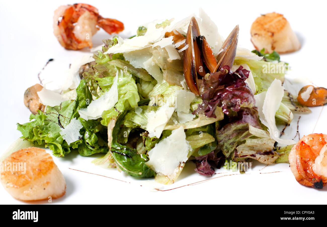 Ungewöhnliche Salat mit Kopfsalat, Parmesan-Käse und Meeresfrüchte. Filetieren der Fische und Garnelen auf den Kanten-Teller Stockfoto