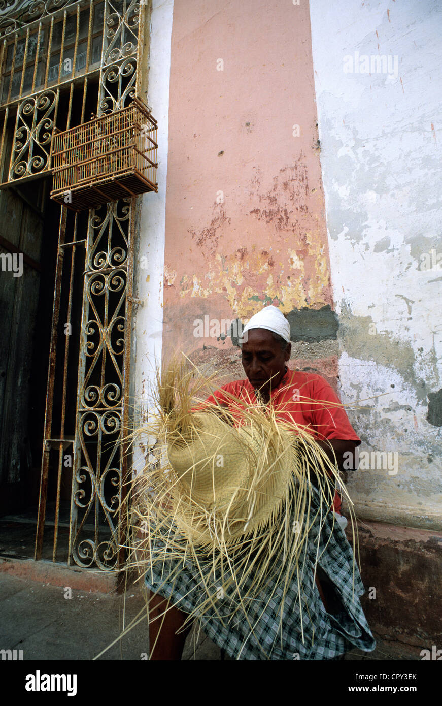 Kuba, Provinz Sancti Spiritus, Trinidad de Cuba aufgeführt als Weltkulturerbe der UNESCO, Frau schlängelt einen Hut vor eine verblichene Fassade Stockfoto