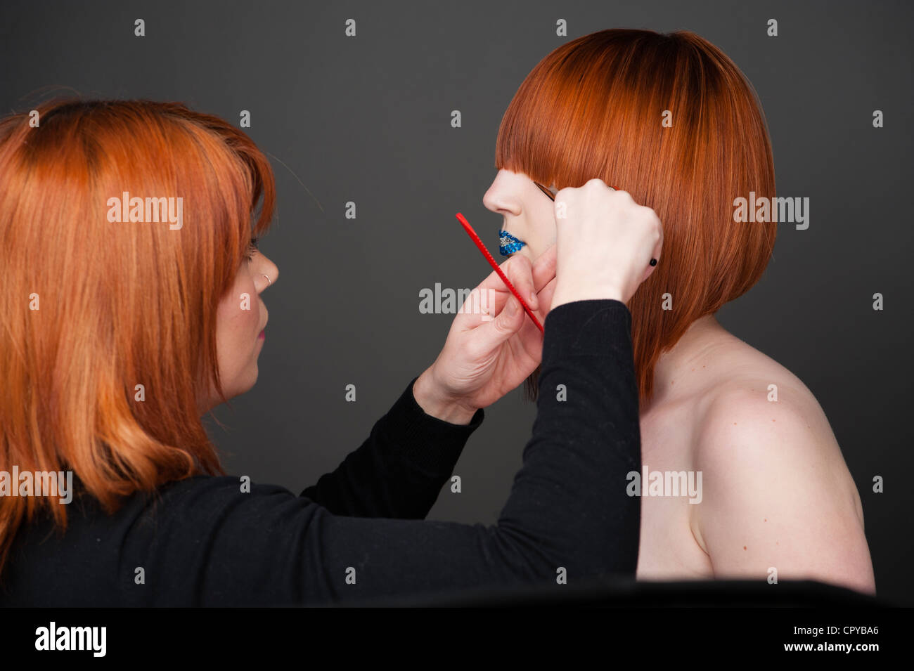 ein Friseur letzte Anpassungen an ein Modell Haar vor einem Mode-Foto-Shooting im studio Stockfoto