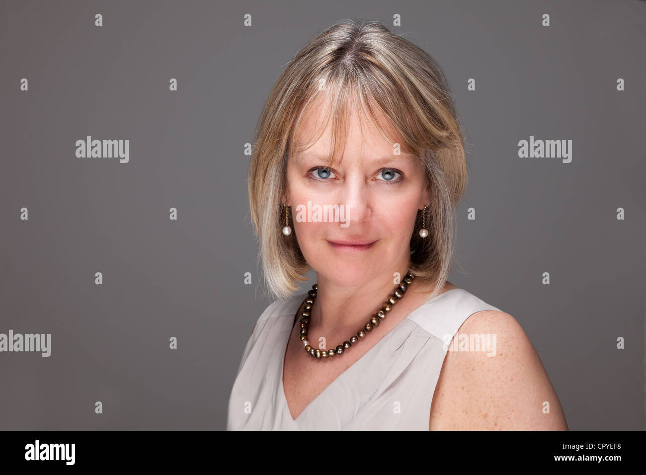 Kopf geschossen Porträt attraktive Reife Frau mit intensiven Blick auf grauem Hintergrund Stockfoto