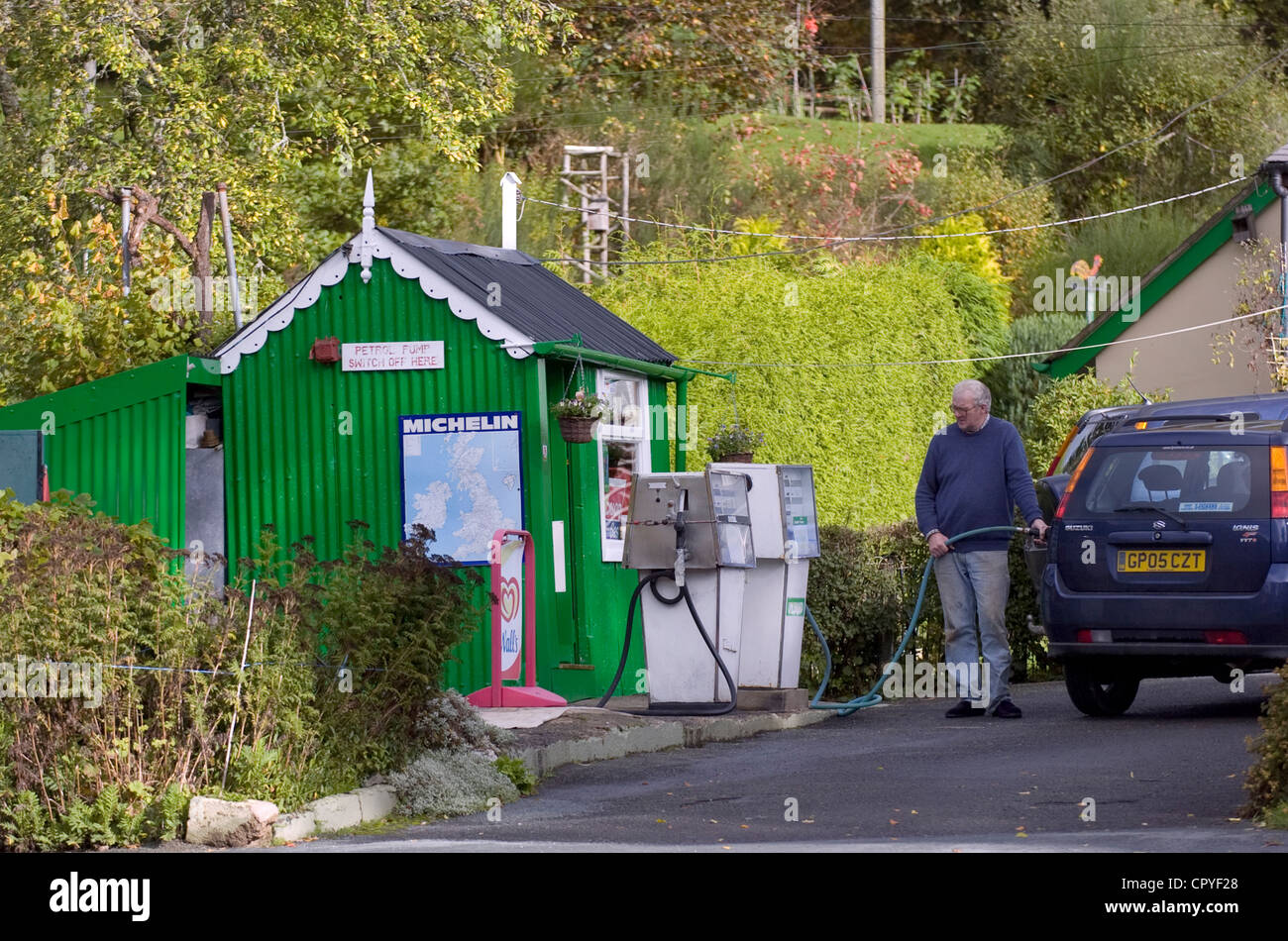 Mann, putting Benzin in seinem Auto an einer alten altmodische ländlichen Tankstelle in North Wales, UK. Stockfoto