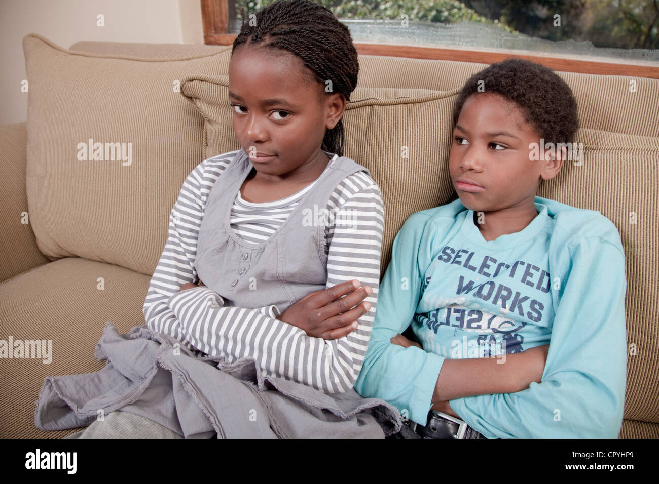 Zwei Kinder sitzen zusammen auf der Couch, Illovo Familie, Johannesburg, Südafrika. Stockfoto