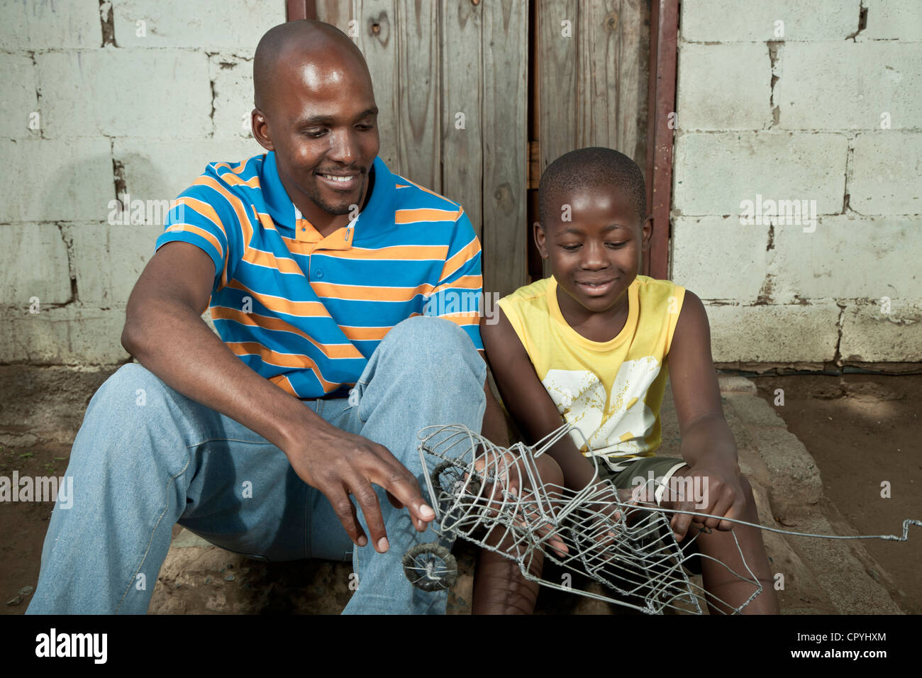 Vater und Sohn sitzen und spielen zusammen im freien Stockfoto