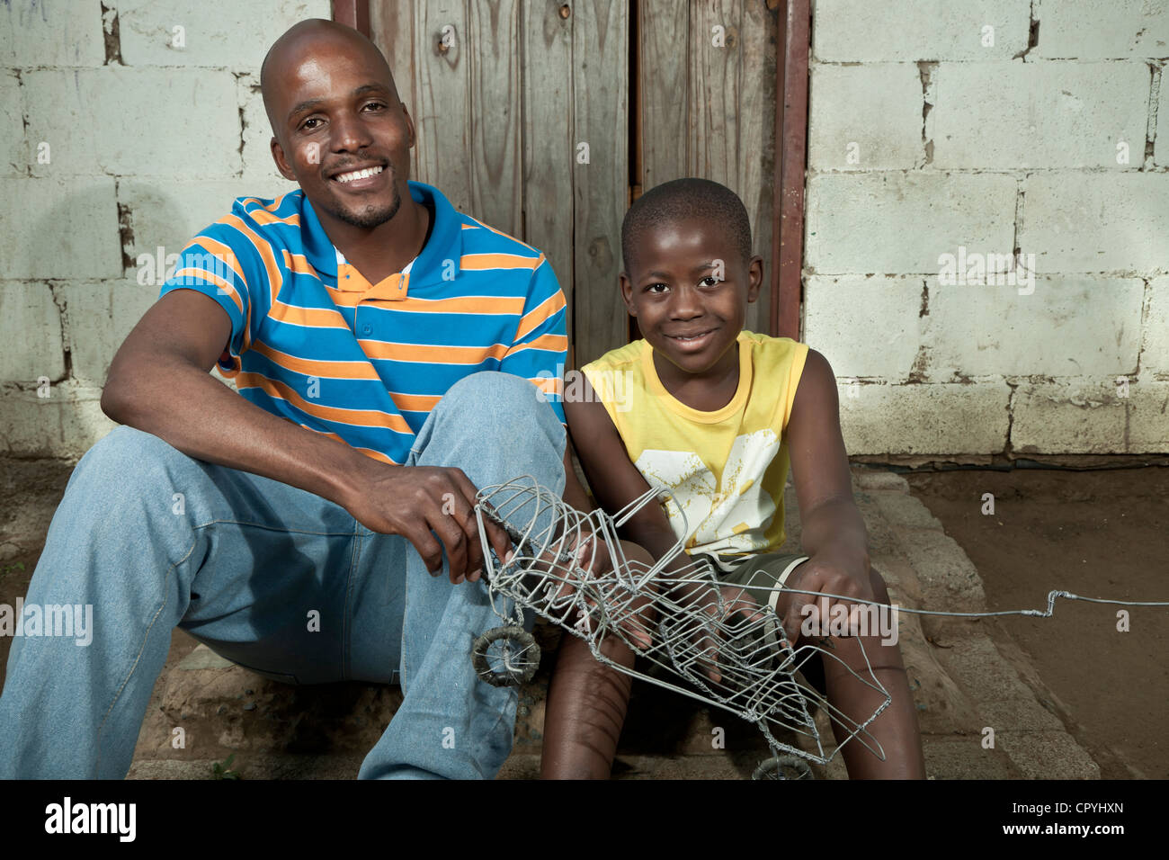 Vater und Sohn sitzen und spielen zusammen im freien Stockfoto