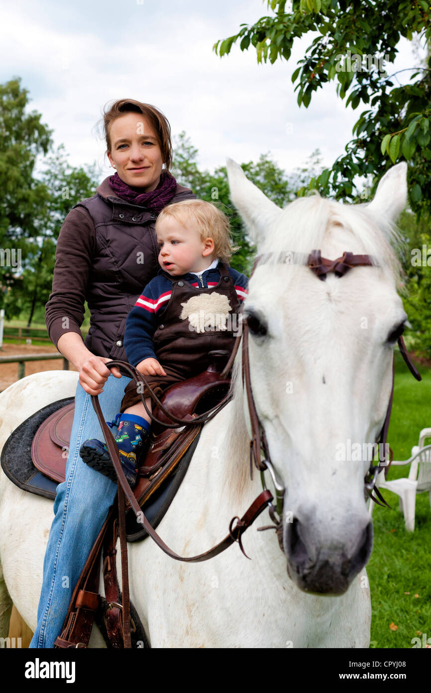 Mutter (35 Jahre) mit Sohn (15 Monate) auf einem grauen Pferd Stockfoto