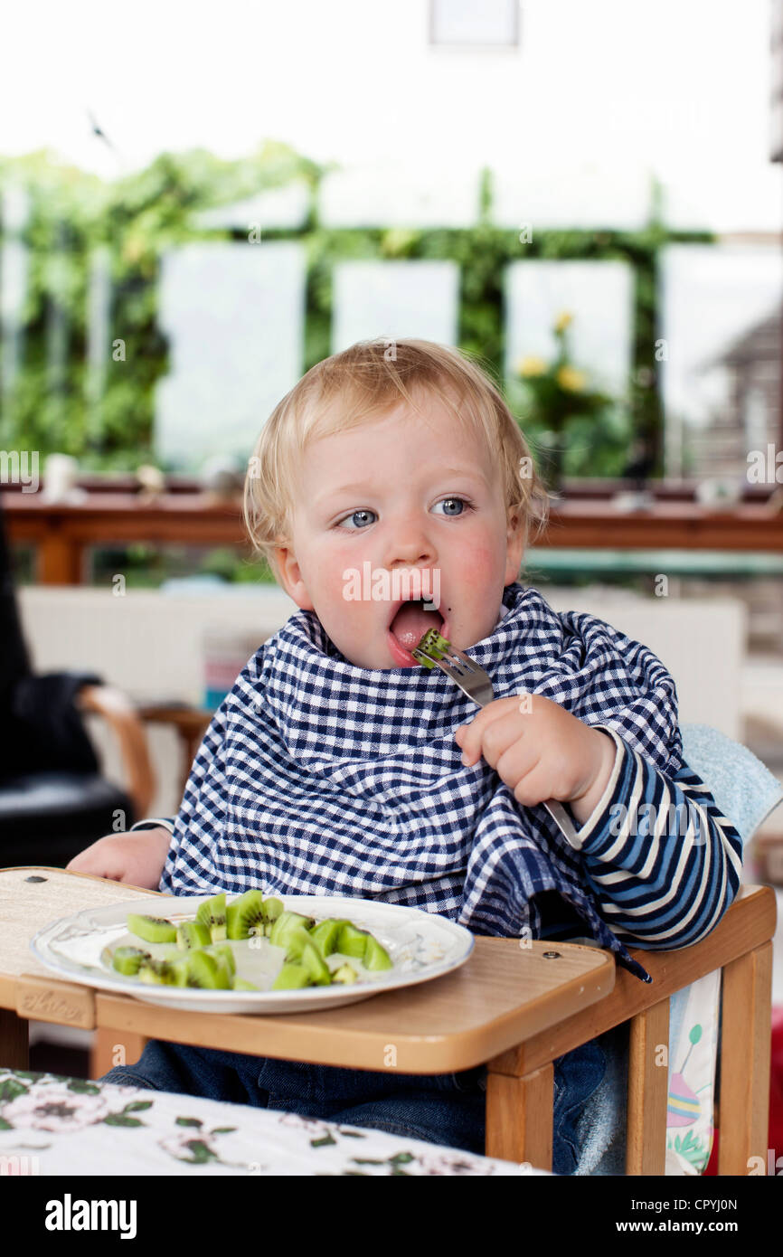 Junge (15 Monate alt) Kiwifrucht mit einer Gabel gegessen Stockfoto