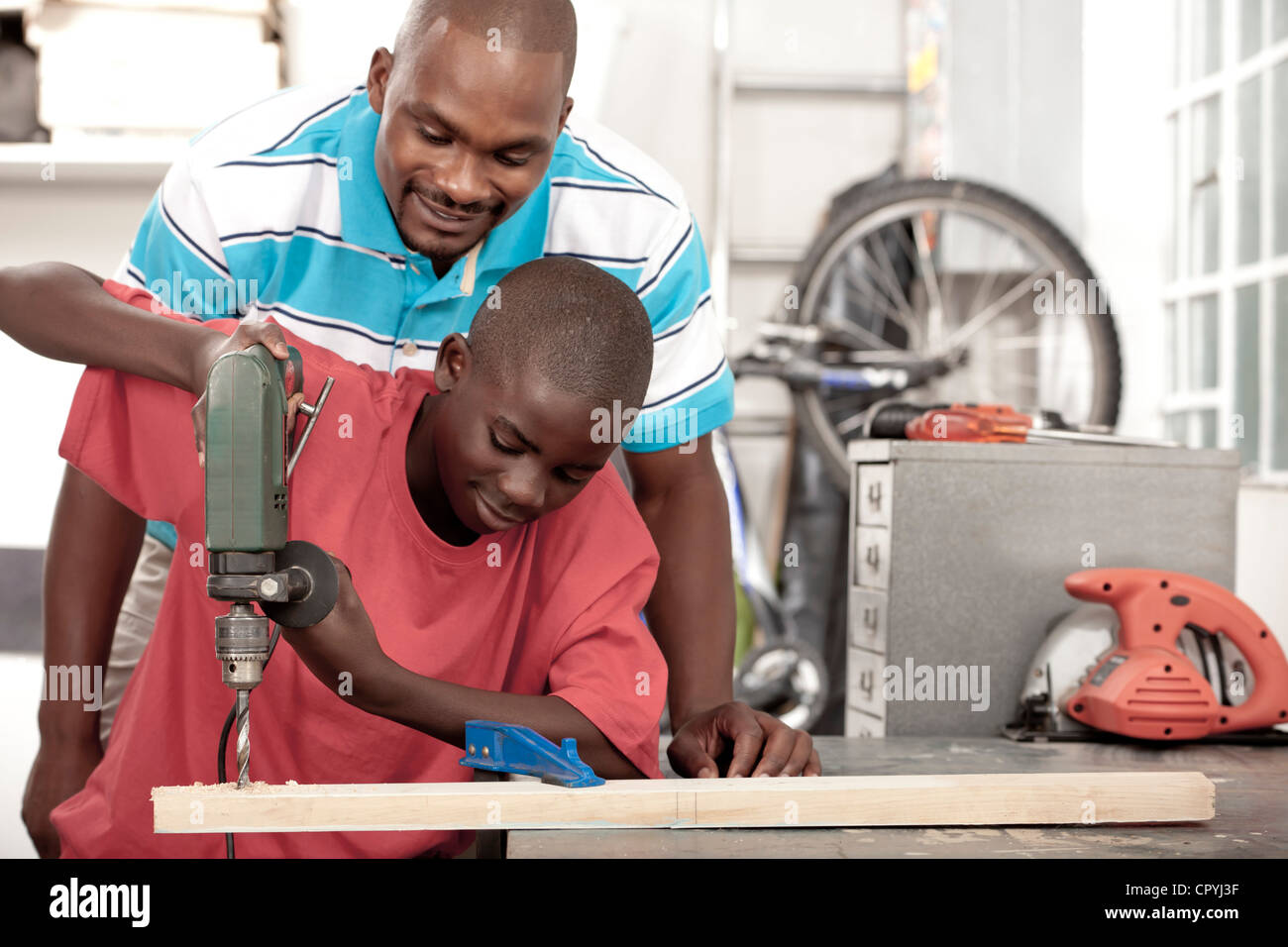 Afrikanischen Vater und Sohn mit einem Bohrer in einem workshop Stockfoto