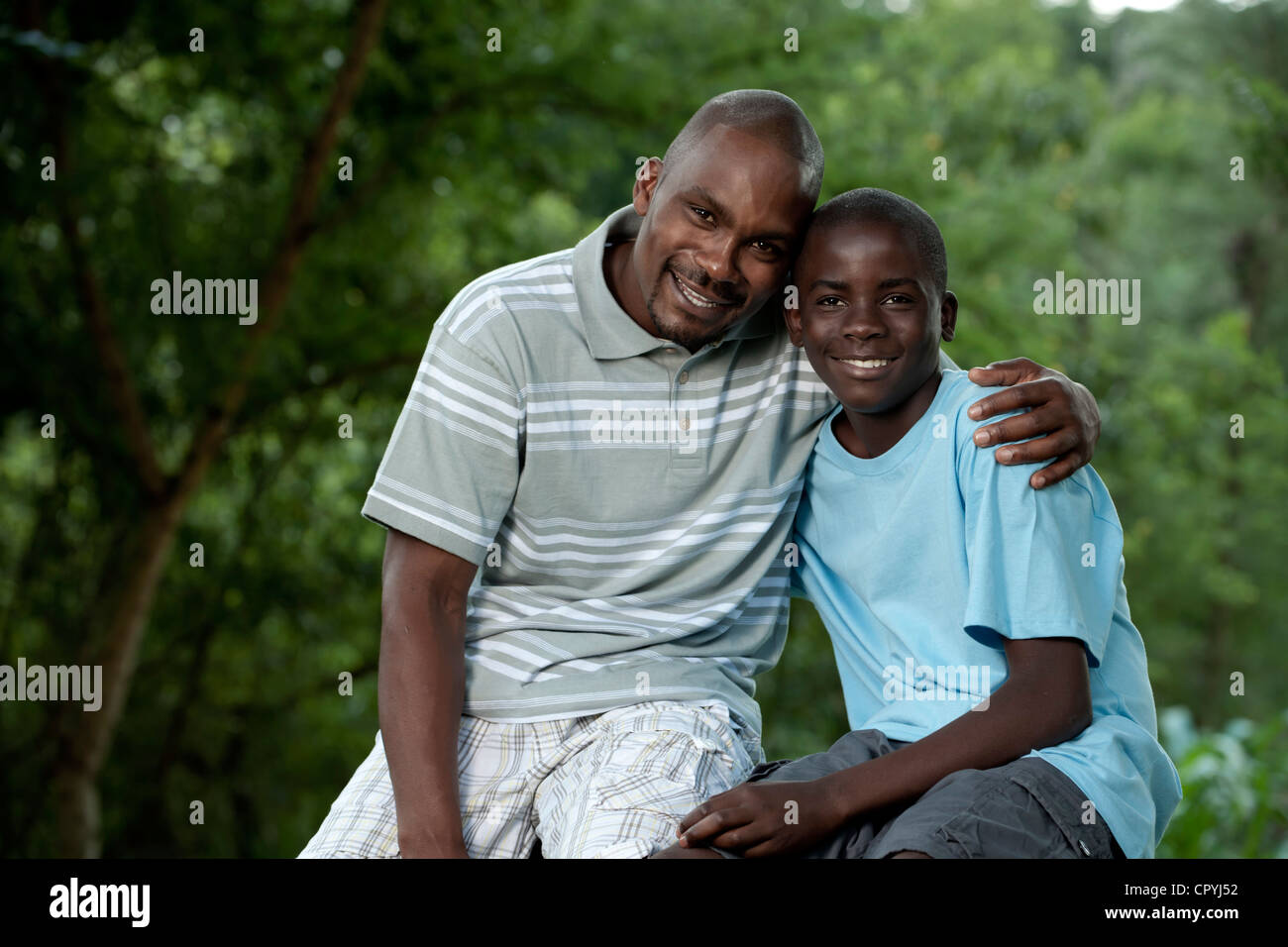 Afrikanischen Vater und Sohn sitzen draußen in einem Garten Stockfoto