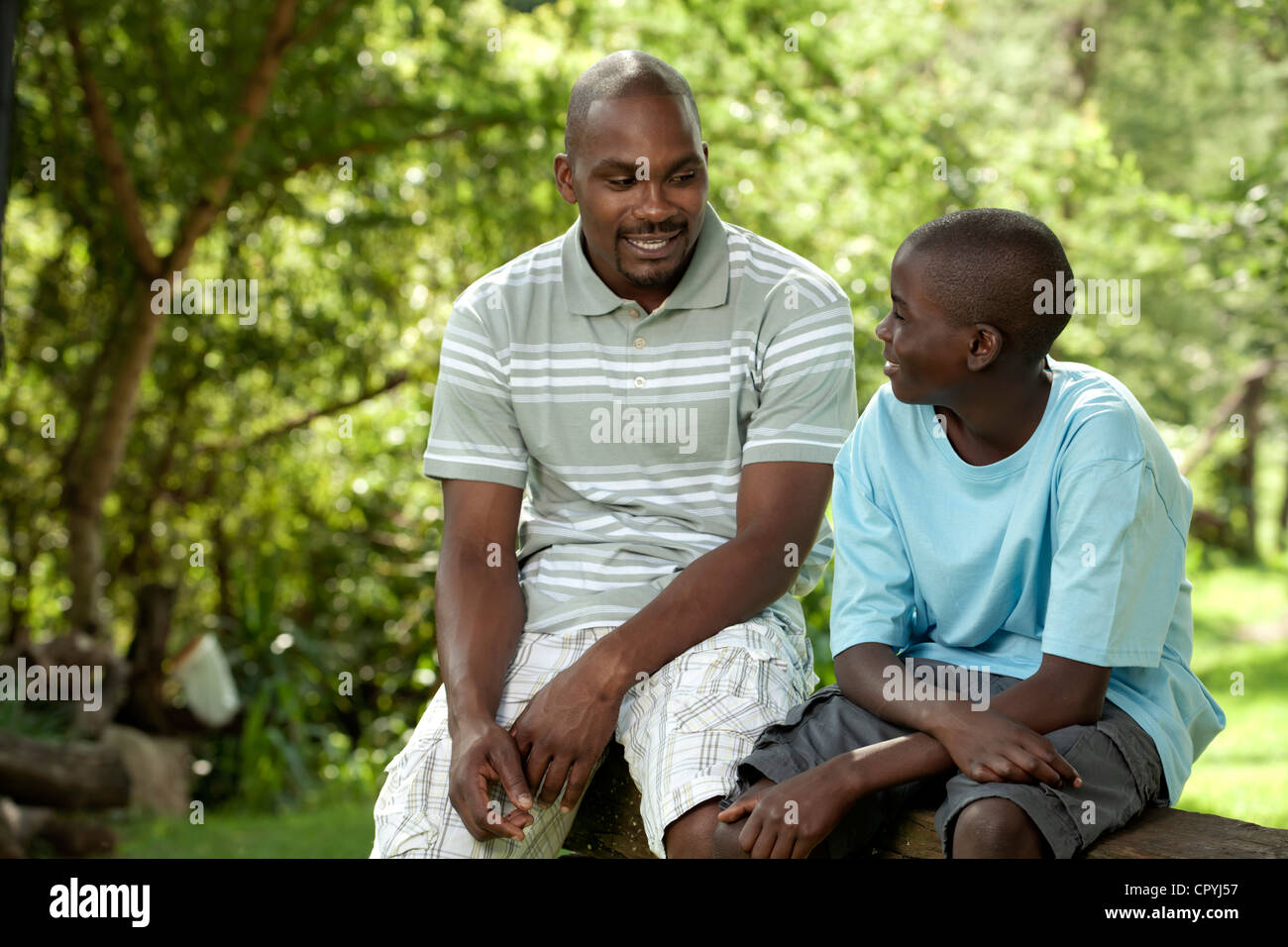 Afrikanischen Vater und Sohn sitzen draußen in einem Garten Stockfoto