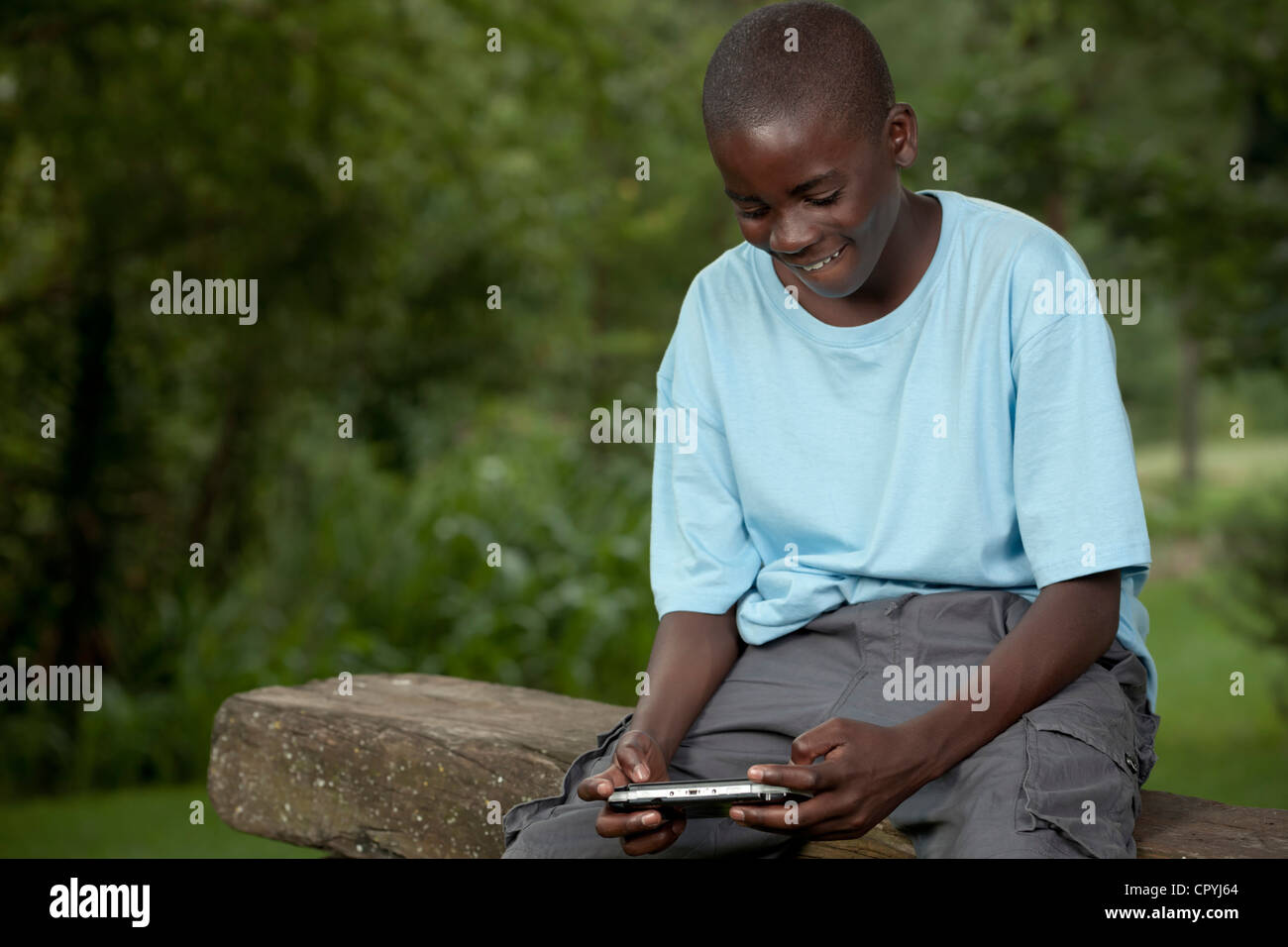 Afrikanische Kind spielt mit einer Spielkonsole außerhalb Stockfoto